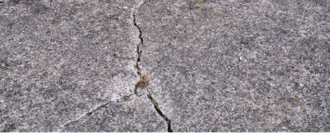 A close-up view of a cracked concrete surface, showing a jagged line running through the rough, gray texture—typical wear that a residential concrete company can expertly repair.