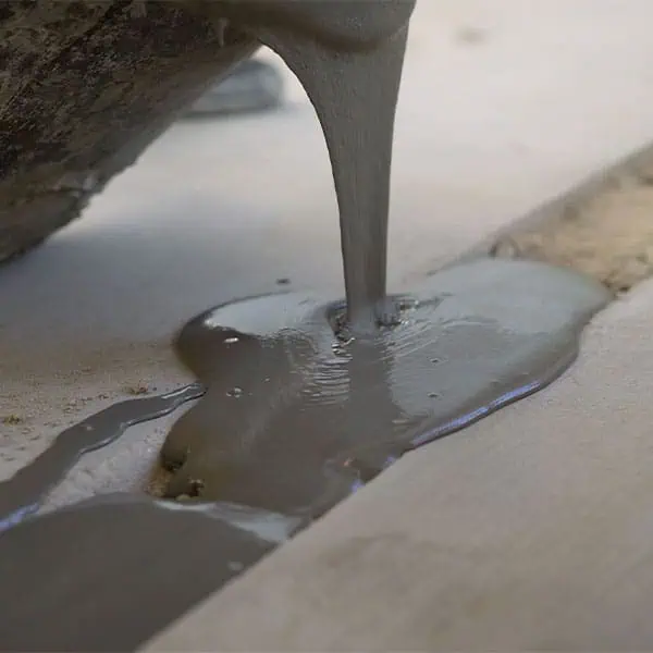 Concrete-Repair Wet cement is being poured into a narrow gap between two concrete surfaces, smoothly filling the space—a common step in concrete driveway repair performed by a skilled concrete company Tampa using precise concrete pumping techniques.